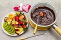 Chocolate fondue. Assorted fresh fruits, two types of chocolate, felt hearts. Ingredients for cooking a sweet romantic dessert.