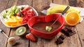 chocolate fondue with fresh fruit in red heart bowl