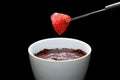 Chocolate fondue on ramekin and fresh and red strawberry on stick