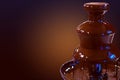 Chocolate fountain fondue. Chocolate fountain on a dark gradient background