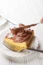 Chocolate frosting with slice of yellow cake being spread