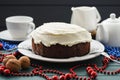 Chocolate fruit cake with cream cheese glasing decorated with garland beads on dark background Royalty Free Stock Photo