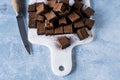 Chocolate ganache truffle squares dusted with cacao being cut into cubes