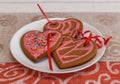 Chocolate gingerbread cookies heart shaped with red and pink icing on white plate Royalty Free Stock Photo