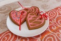 Chocolate gingerbread cookies heart shaped with red and pink icing on white plate Royalty Free Stock Photo