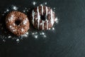 Chocolate and glazed donuts, white, brown on black stone, top view