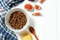 Chocolate granola in a white bowl in a composition with honeycombs, a spoon, figs on white wooden background. Healthy breakfast