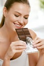 Chocolate. Happy Woman Biting Chocolate Bar.