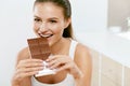 Chocolate. Happy Woman Biting Chocolate Bar.