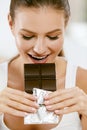 Chocolate. Happy Woman Biting Chocolate Bar. Royalty Free Stock Photo