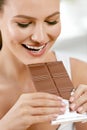 Chocolate. Happy Woman Biting Chocolate Bar. Royalty Free Stock Photo