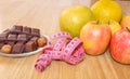 Chocolate with hazelnuts, a meter and fruits, apples, bananas, greyfruit. Chocolate or fruit diet.