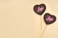 Chocolate heart shaped lollipops with word Love on beige background, flat lay. Space for text Royalty Free Stock Photo