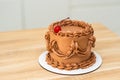 A chocolate holiday cake decorated with a cream pattern and a cherry Royalty Free Stock Photo