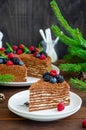 Chocolate honey cake with cream and fresh berries on top on a white plate on a wooden background. Cake for Christmas and New Year Royalty Free Stock Photo