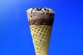 Chocolate ice cream cone on blue background