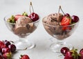 Chocolate ice cream scoops in transparent cups with fresh cherries and strawberries. Tasty dessert