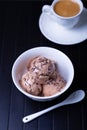 Chocolate ice cream with chocolate sprinkle in a white bowl on a black background. Three balls ice cream and a cup of coffee. Royalty Free Stock Photo