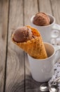 Chocolate ice cream in waffle cone in rustic wooden background