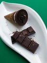 Photo of chocolate ice cream in waffle cones. Served on white plate on green background with dark bitter chocolate Royalty Free Stock Photo