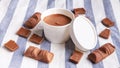 Chocolate ice cream in a white paper cup with many kinds of chocolate around on white and blue stripe fabric Royalty Free Stock Photo