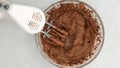 Chocolate icing in a glass bowl, mixing ingredients together using an electric mixer