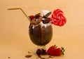 Chocolate indulgent extreme milkshake with brownie cake, strawberries, cherries, candy with heart form, a plastic straw