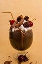 Chocolate indulgent extreme milkshake with brownie cake, strawberries, cherries, and a plastic straw with milk foam on