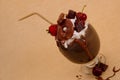 Chocolate indulgent extreme milkshake with brownie cake, strawberries, cherries, and a plastic straw with milk foam on