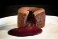 CHOCOLATE LAVA CAKE WITH CHERRY FILLING SERVED ON A WHITE PLATE