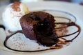 Chocolate lava cake with vanilla ice cream served on white plate, dress with chocolate syrup and brown sug