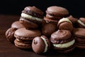 Chocolate macarons of various sizes. Brown background Royalty Free Stock Photo