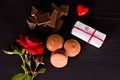 Chocolate macaroons, gift and rose flower on a dark background. Royalty Free Stock Photo