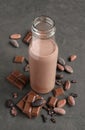 Chocolate milk in a glass bottle with pieces of chocolate bar and cacao beans