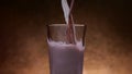 Chocolate milk and milk streams pour into glass, blending and mixing