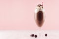 Chocolate milkshake with sweet whipped cream, straw and candies in modern stylish pink interior on white wooden table, copy space.