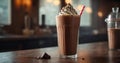 Chocolate milkshake with whipped cream in a tall glass with a straw on a dark background