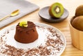 Chocolate Moelleux cake or molten cake with kiwi fruit, by a golden spoon and bowl with entire kiwi fruit over a wooden background Royalty Free Stock Photo