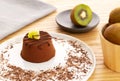 Chocolate Moelleux cake or molten cake, with kiwi fruit, by a bowl with entire kiwi fruit over a wooden background Royalty Free Stock Photo