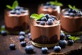 Chocolate mousse with blueberries and mint in a glass on a wooden background. Selective focus, Chocolate mousse garnished with