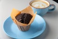 Chocolate muffin on blue plate and cup of cappuccino