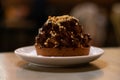 Chocolate muffin cake with nuts and choco cream on white plate on wooden table. Dessert chocolate