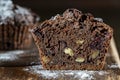 Chocolate muffin with red cherries and walnuts on a wooden table sprinkled with powdered sugar, closeup. Homemade delicious Royalty Free Stock Photo