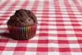 Chocolate muffin on a red and white tablecloth.