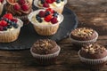 Chocolate muffins with nuts and vanilla muffins with mix of fresh berries on wooden table Royalty Free Stock Photo