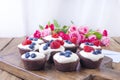 Chocolate muffins with raspberries and blueberries, and white cheese cream, on a brown wooden board. A bouquet of fresh pink roses Royalty Free Stock Photo