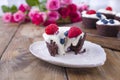 Chocolate muffins with raspberries and blueberries, and white cheese cream, on a brown wooden board. A bouquet of fresh pink roses Royalty Free Stock Photo