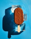 Chocolate nut ice cream on ice cubes on a blue background. Sunlight. Summer concept Royalty Free Stock Photo