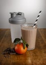 Chocolate orange milkshake, ingredients and shaker with paper straw on a wooden table top Royalty Free Stock Photo