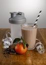 Chocolate orange milkshake, ingredients, tape measure and shaker with paper straw on a wooden bench top Royalty Free Stock Photo